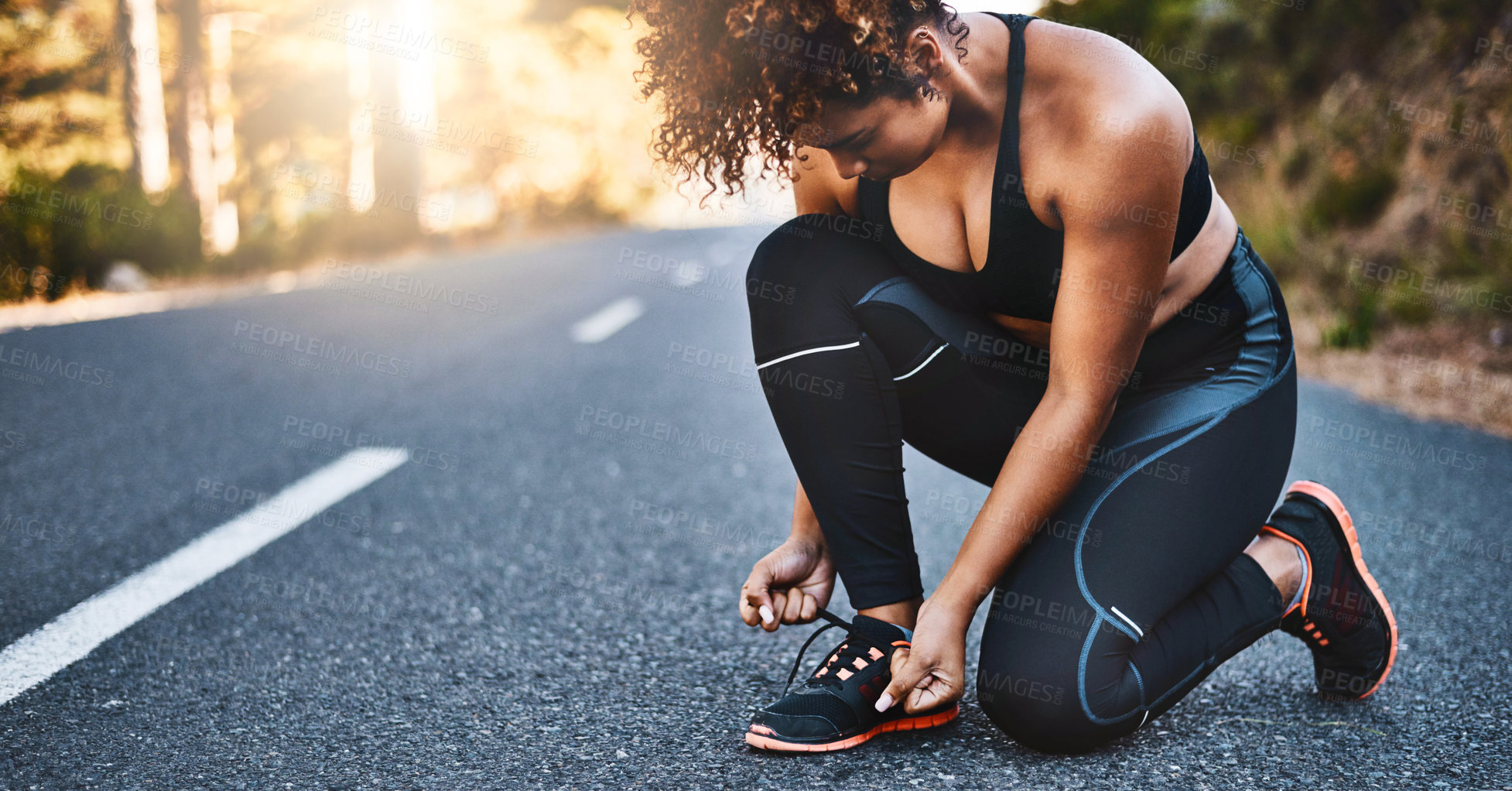 Buy stock photo Shot of a sporty young woman tying her shoelaces before her run
