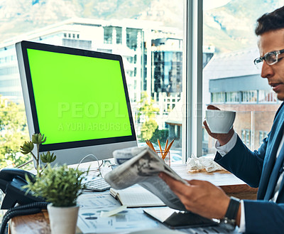 Buy stock photo Shot of a focused young businessman seated at his desk  while drinking coffee and reading a newspaper in the office