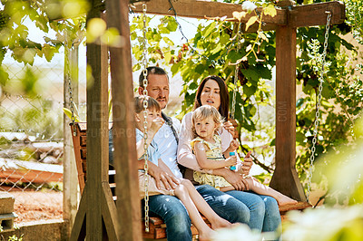 Buy stock photo Shot of a family of four relaxing together on a garden swing