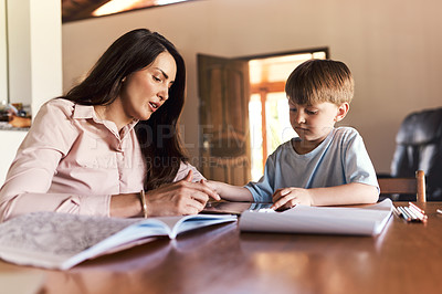 Buy stock photo Shot of a mother helping her son with his homework