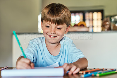 Buy stock photo Shot of a little boy sitting at a desk and writing on a notepad at home