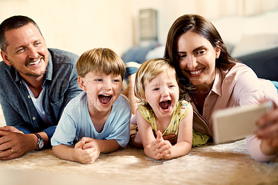 Buy stock photo Shot of a happy young family taking selfies together at home