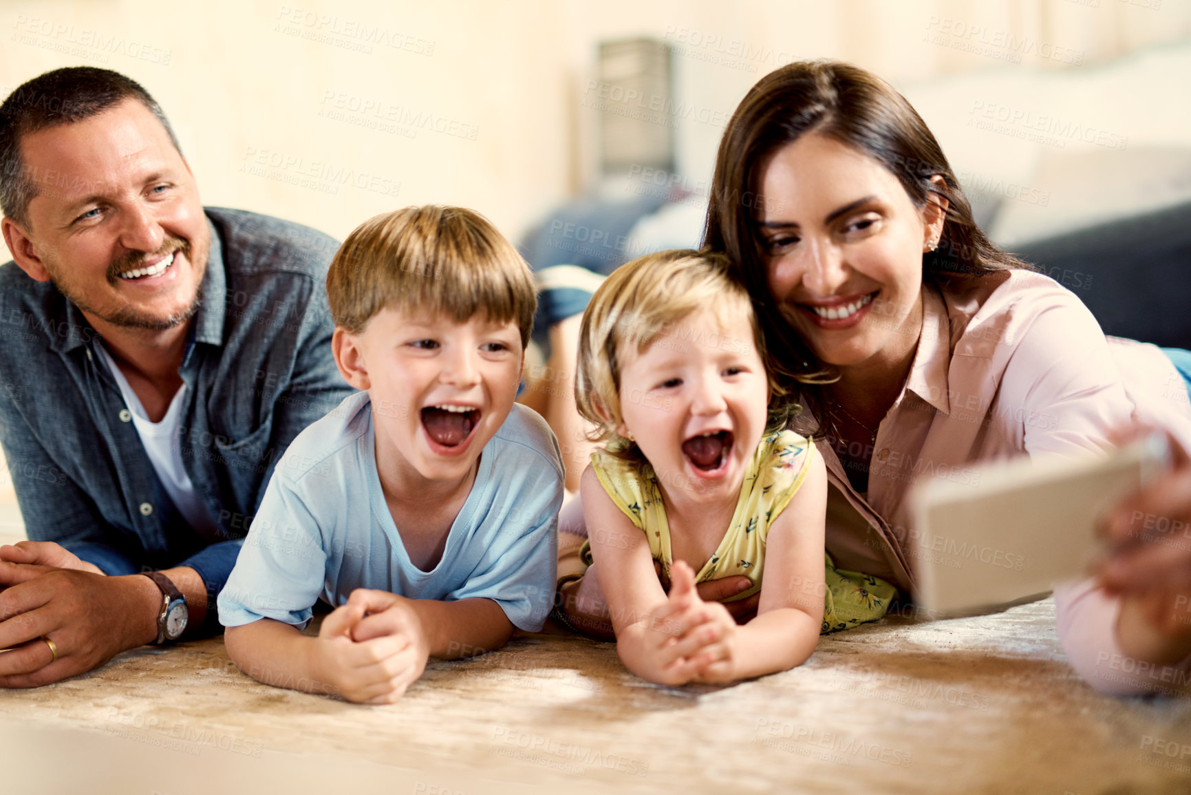 Buy stock photo Shot of a happy young family taking selfies together at home