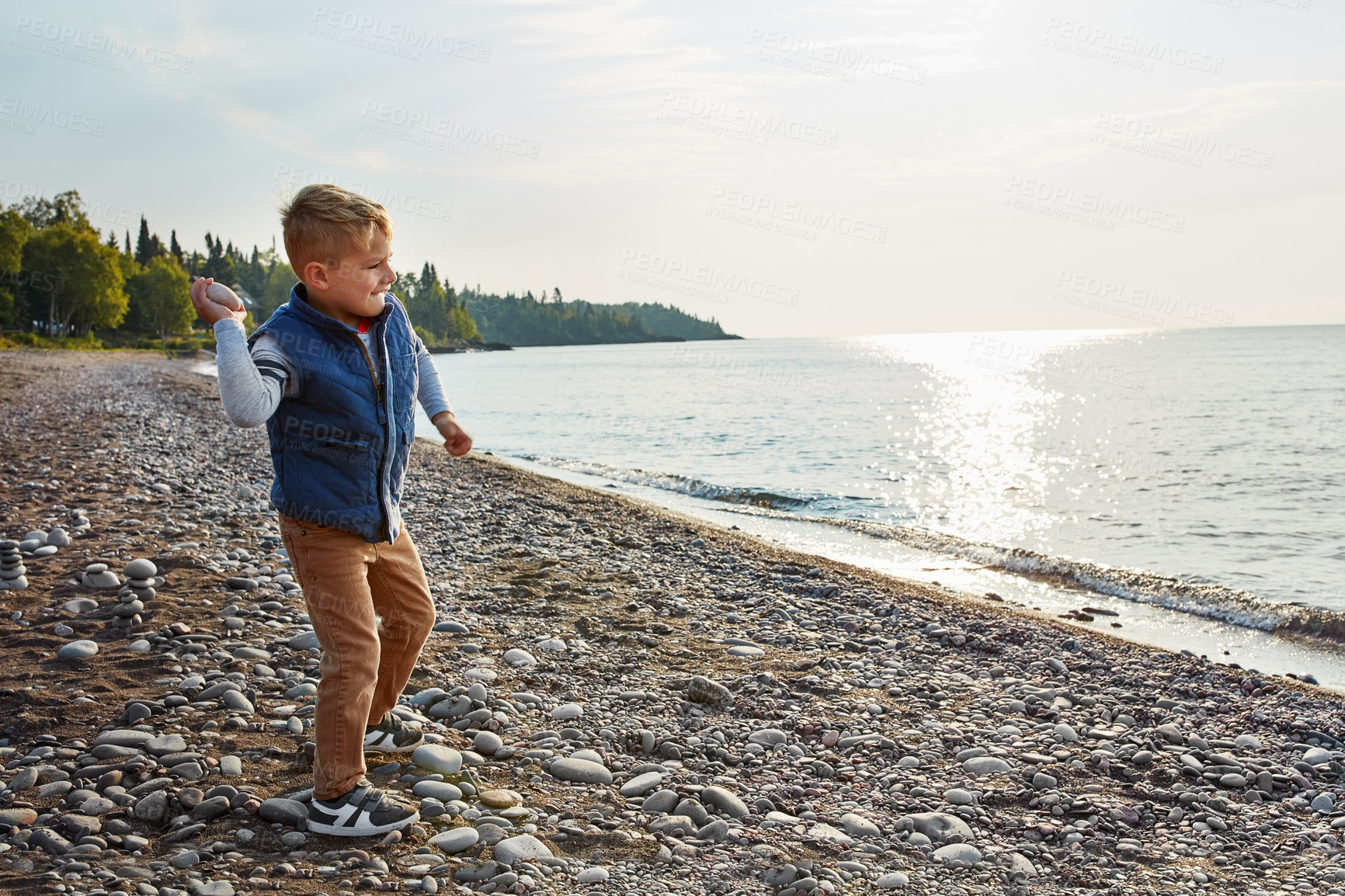 Buy stock photo Full length shot of an adorable young boy playing outside near a lake