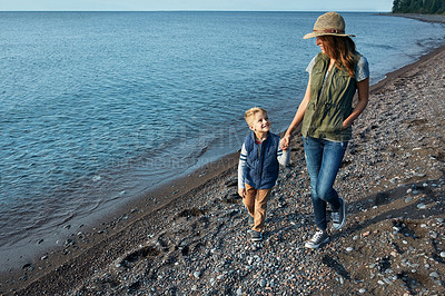 Buy stock photo Shot of a young woman and her son enjoying a walk by the water