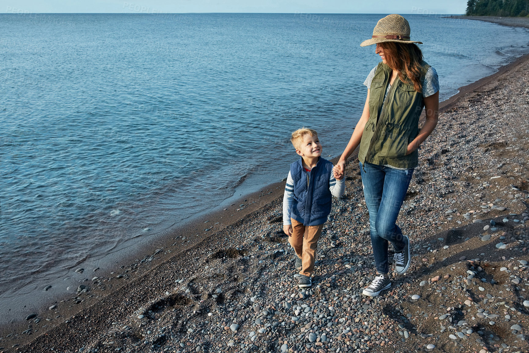 Buy stock photo Shot of a young woman and her son enjoying a walk by the water