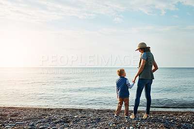 Buy stock photo Shot of a young woman and her son enjoying a walk by the water