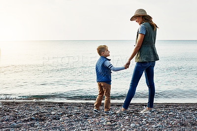 Buy stock photo Shot of a young woman and her son enjoying a walk by the water