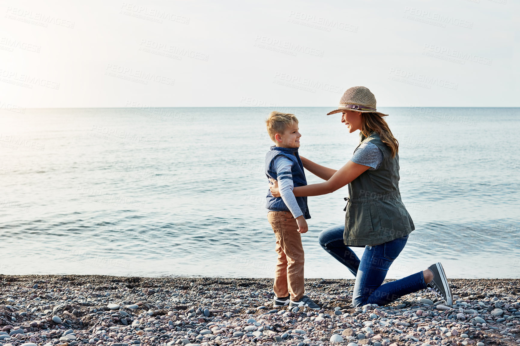 Buy stock photo Shot of a young woman and her son enjoying a walk by the water