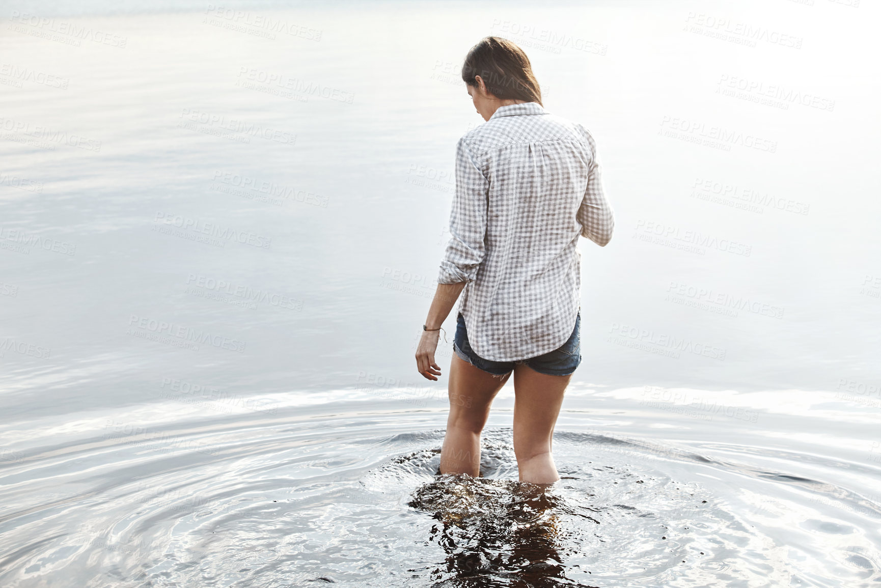 Buy stock photo Rearview shot of a young woman standing in a lake