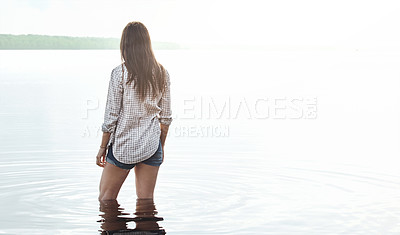 Buy stock photo Rearview shot of a young woman standing in a lake