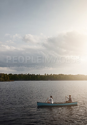 Buy stock photo Shot of a young couple rowing a boat out on the lake