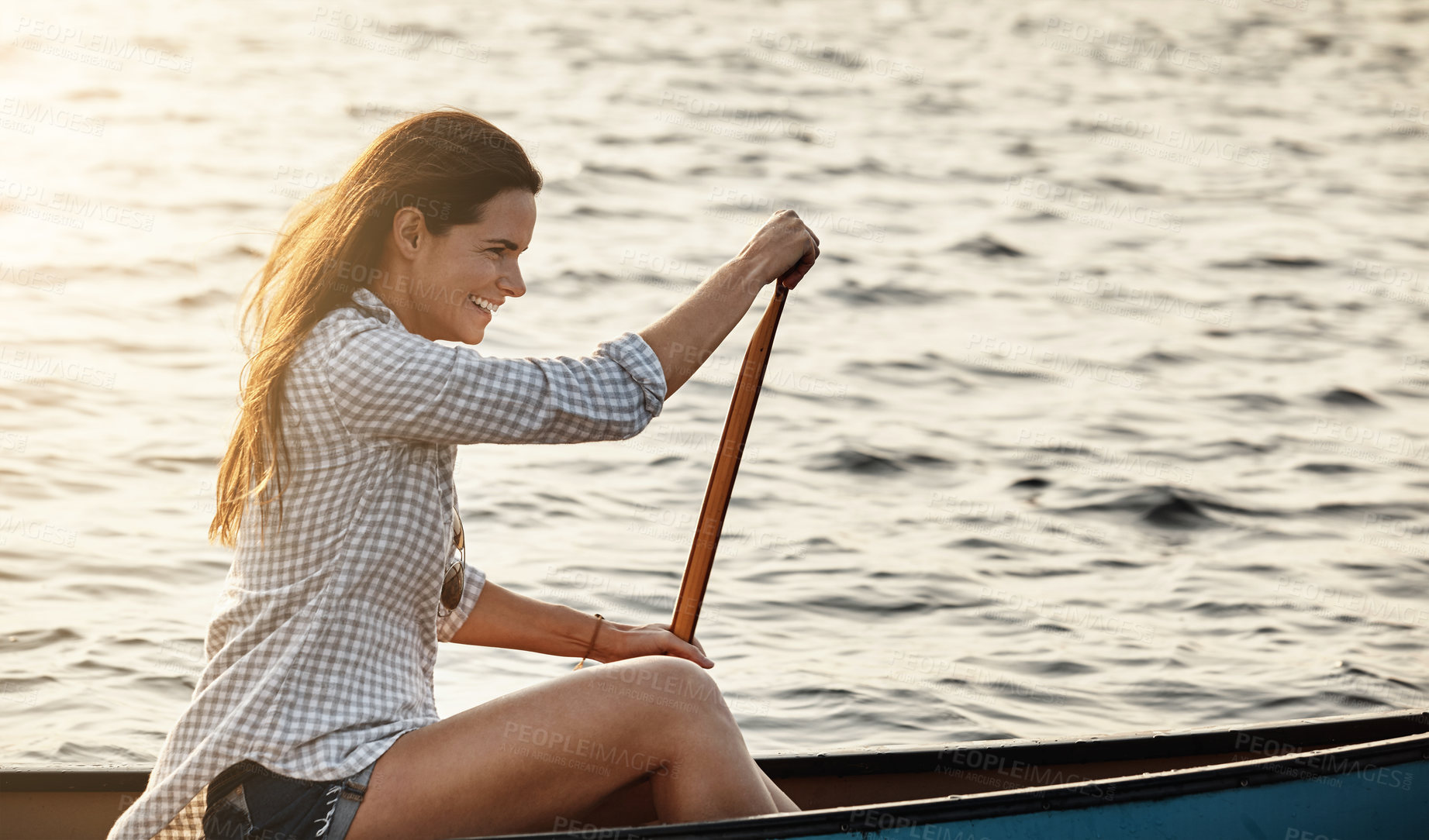 Buy stock photo Shot of a beautiful young woman rowing a boat out on the lake