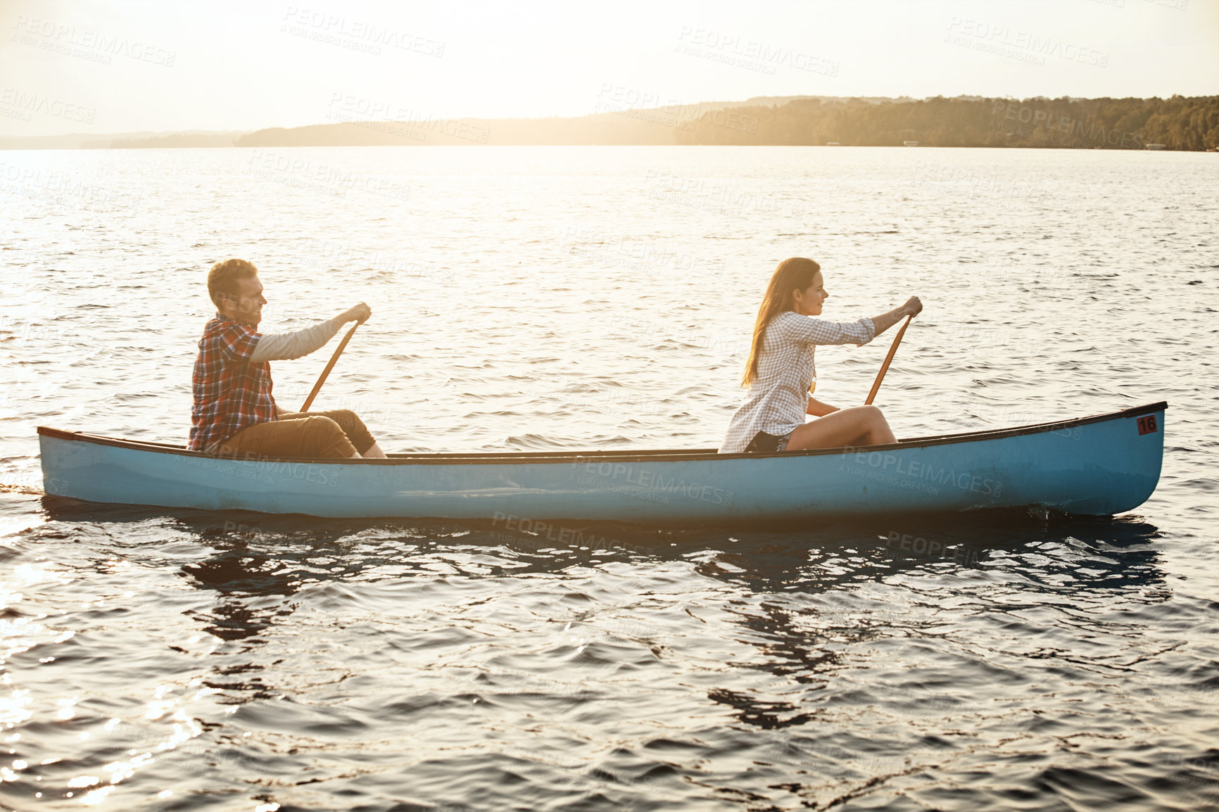 Buy stock photo Shot of a young couple rowing a boat out on the lake