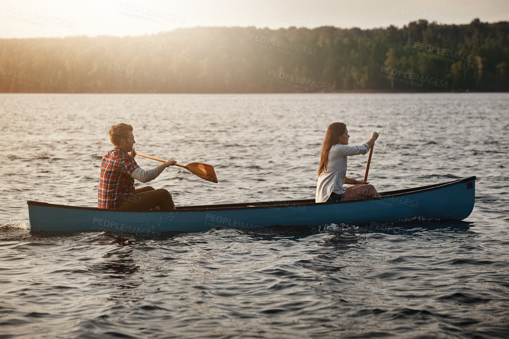 Buy stock photo Shot of a young couple rowing a boat out on the lake