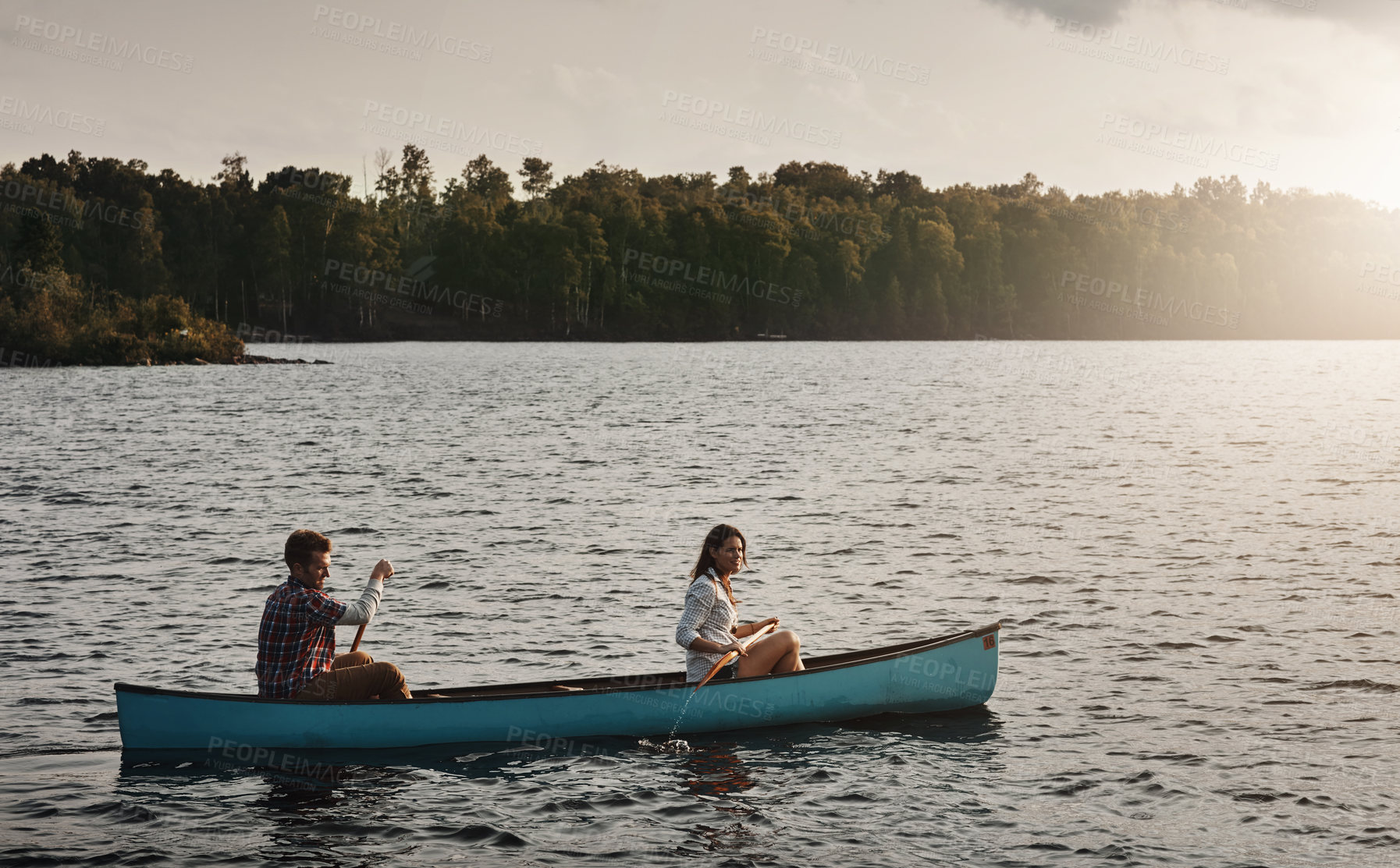 Buy stock photo Shot of a young couple rowing a boat out on the lake