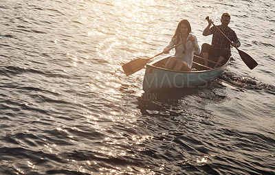 Buy stock photo Shot of a young couple rowing a boat out on the lake