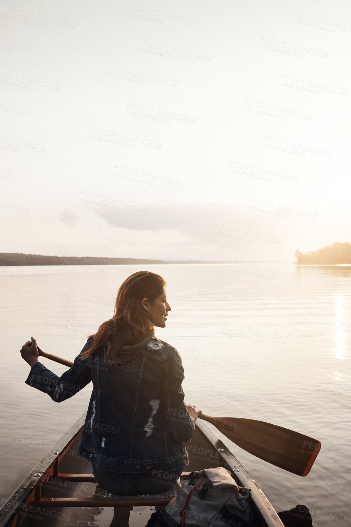 Buy stock photo Rearview shot of a young woman enjoying a canoe ride at the lake