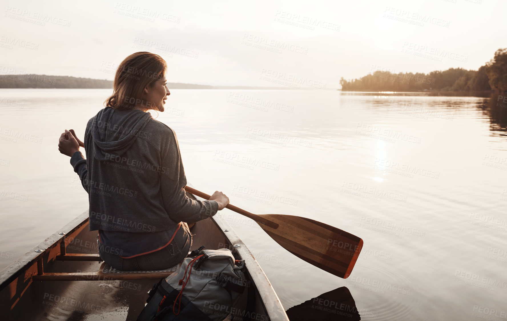 Buy stock photo Rearview shot of a young woman enjoying a canoe ride at the lake