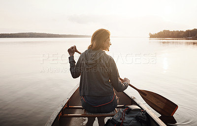 Buy stock photo Rearview shot of a young woman enjoying a canoe ride at the lake