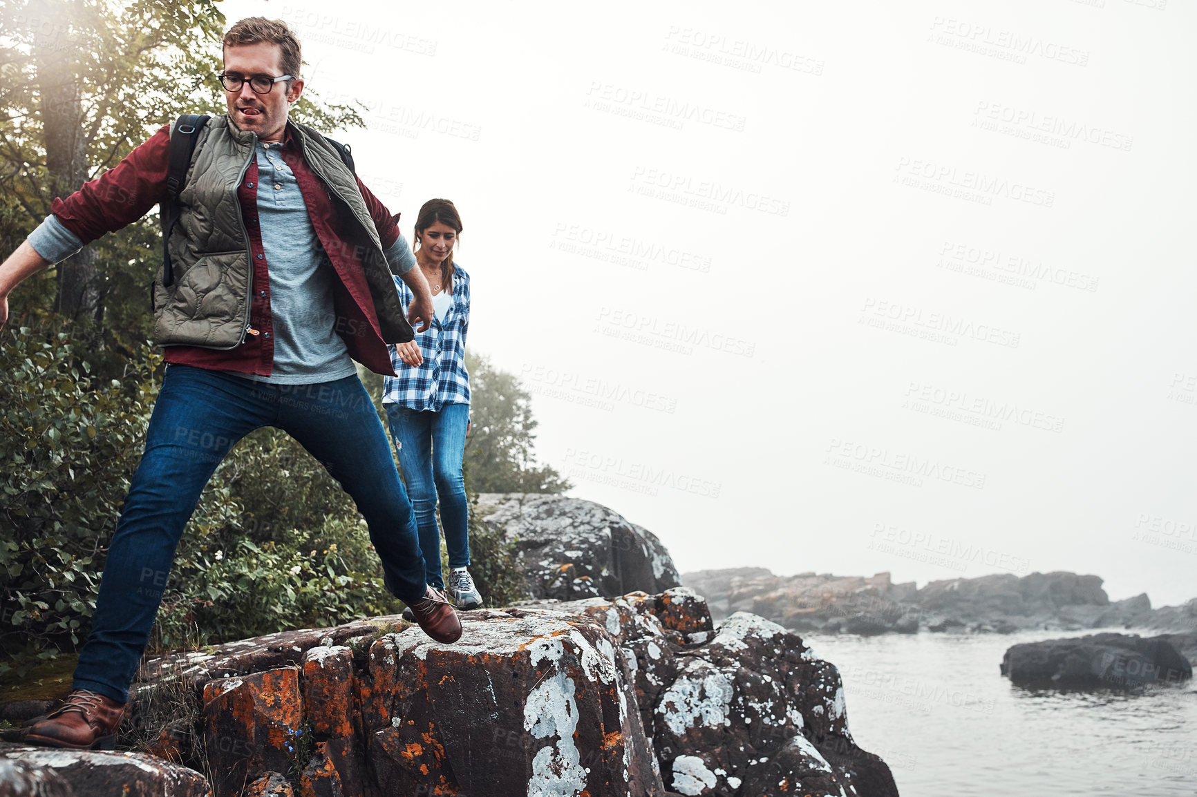 Buy stock photo Shot of a couple crossing over rocks while out exploring nature