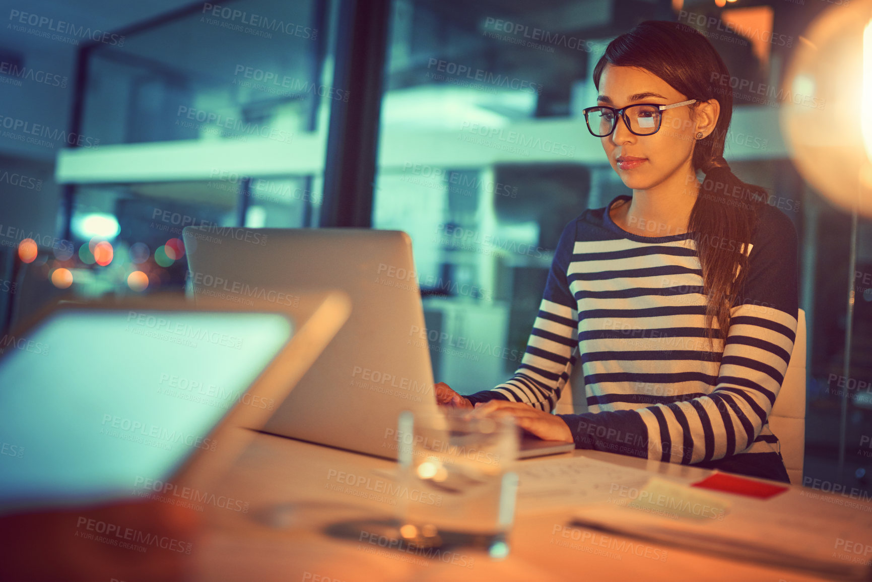 Buy stock photo Shot of a young designer working late in a laptop in an office