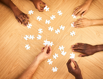 Buy stock photo Cropped shot of a group of businesspeople completing a puzzle together on a table