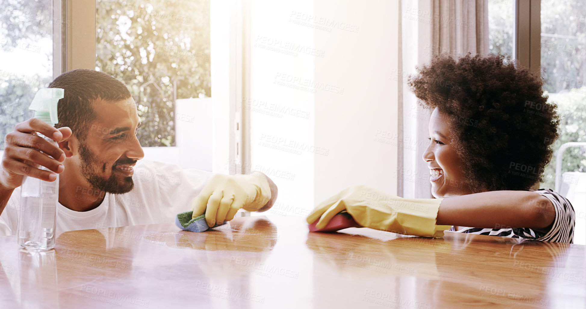 Buy stock photo Shot of a cheerful young couple cleaning the surface of a table with cleaning equipment together at home