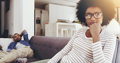 Buy stock photo Shot of a annoyed looking woman seated on a couch resting with her chin on her fist while ignoring her boyfriend at home
