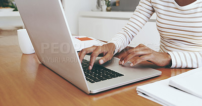 Buy stock photo Shot of an unrecognizable woman's hands typing on a laptop while being seated next to a table at home