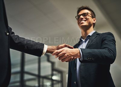 Buy stock photo Low angle shot of two businessmen shaking hands in an office