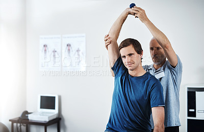 Buy stock photo Shot of a physiotherapist helping a patient work through his recovery with weights