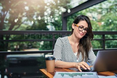 Buy stock photo Cropped shot of an attractive young businesswoman working on her laptop while sitting outdoors at a cafe