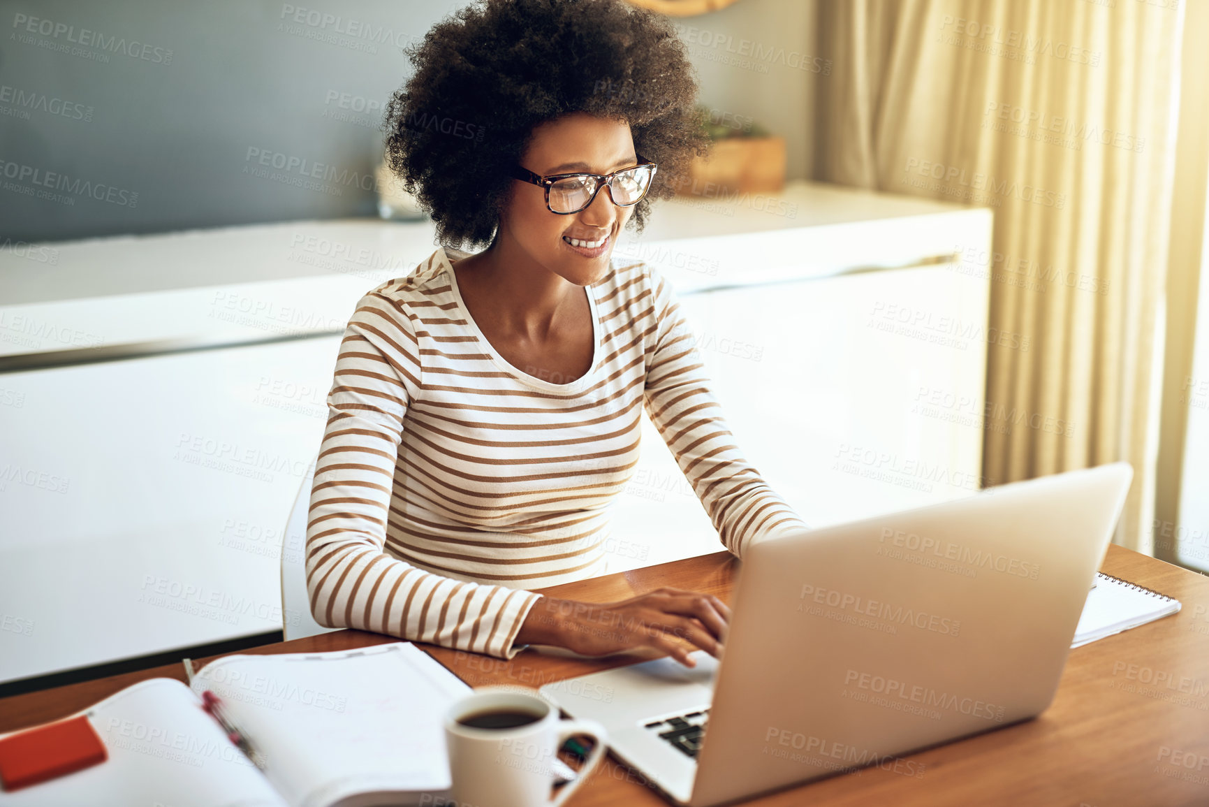 Buy stock photo Shot of a confident young woman working on her laptop while drinking a cup of coffee at home during the day