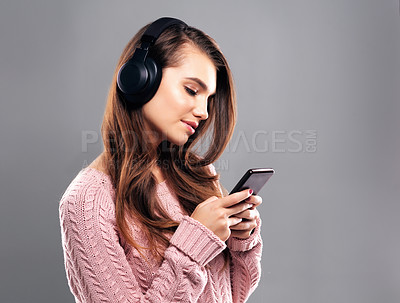 Buy stock photo Studio shot of a beautiful young woman listening to music against a gray background