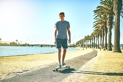 Buy stock photo Full length shot of a young boy skating on a pathway alongside a lagoon