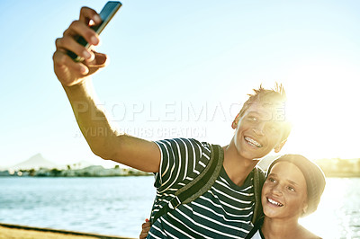 Buy stock photo Cropped shot of two young brothers taking selfies outside with a lagoon in the background