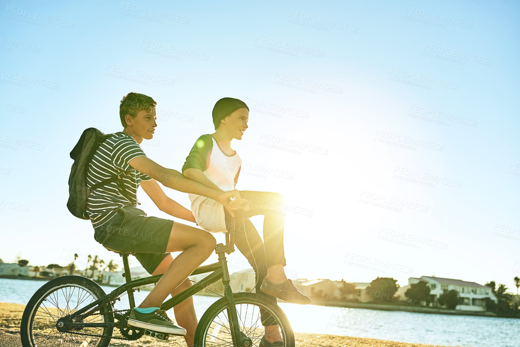 Buy stock photo Cropped shot of a young boy giving his younger brother a lift on a bicycle outside
