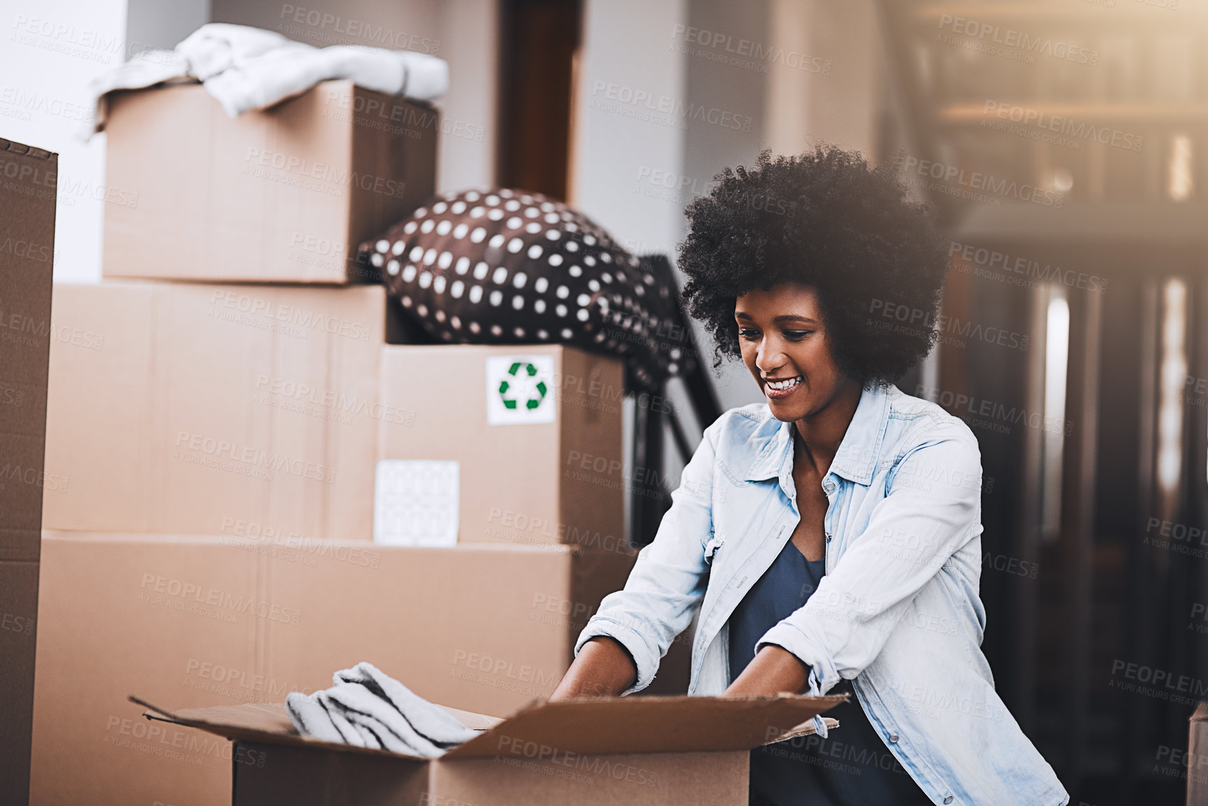 Buy stock photo Cropped shot of an attractive young woman unpacking boxes in her new home