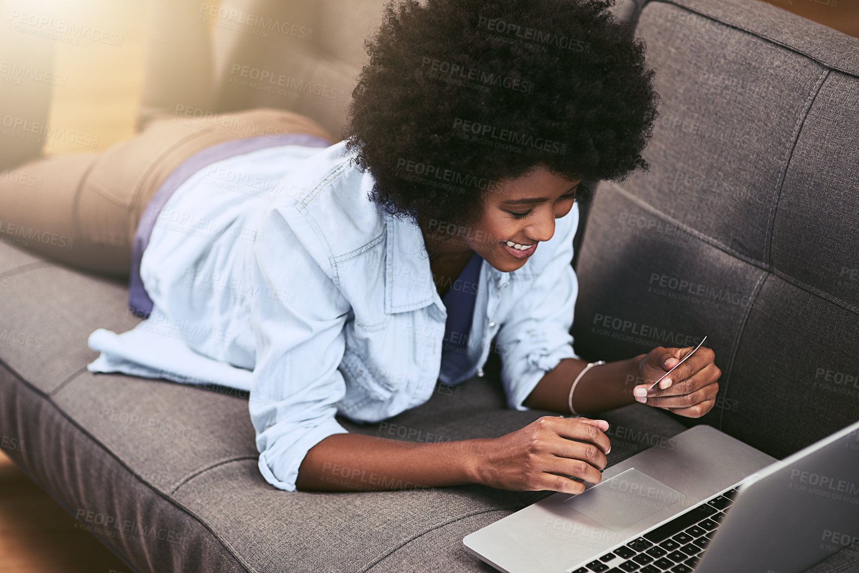 Buy stock photo Shot of a young woman using a laptop and credit card on the sofa at home