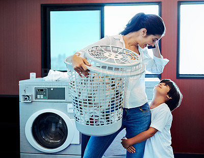 Buy stock photo Cropped shot of a young attractive mother doing laundry with her son at home