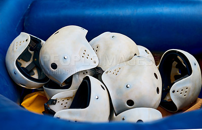 Buy stock photo Closeup of a pile of protective helmets lying inside of a rubber boat outside during the day