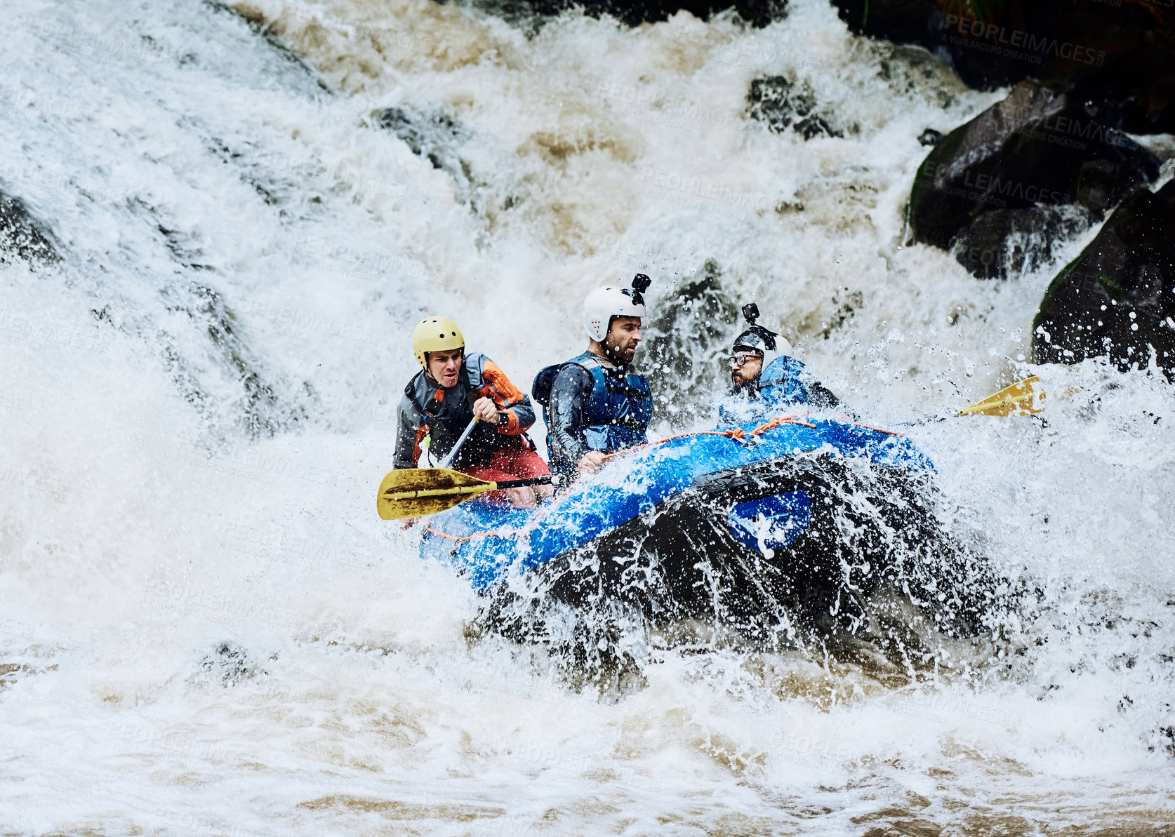 Buy stock photo Shot of a group of determined young men on a rubber boat busy paddling on strong river rapids outside during the day