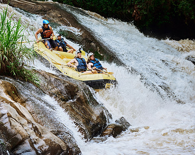 Buy stock photo Shot of a group of determined young men on a rubber boat busy paddling on strong river rapids outside during the day