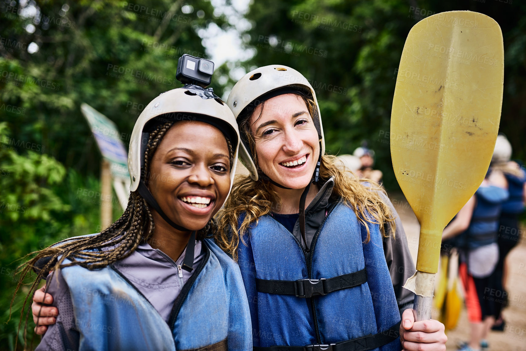 Buy stock photo Portrait of two cheerful young women wearing protective gear while holding a rowing paddle outside during the day