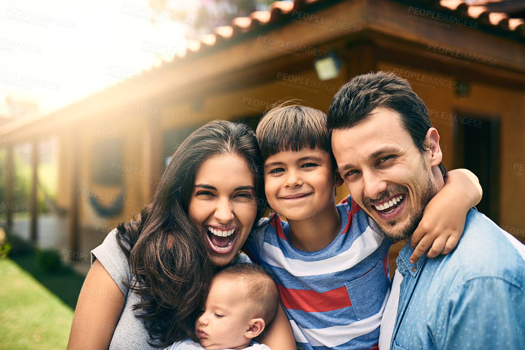 Buy stock photo Cropped portrait of a happy young family of four outside with their house in the background