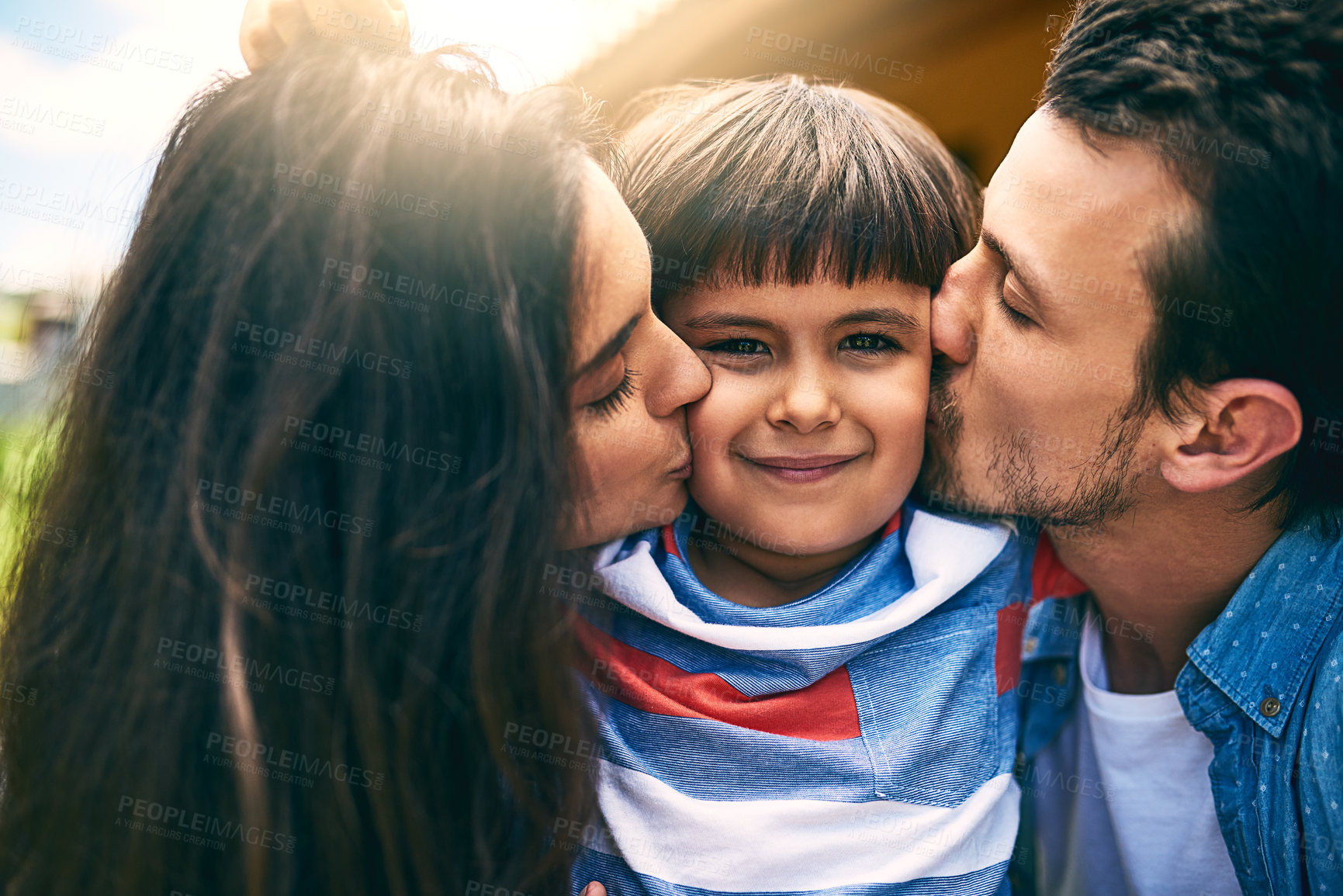 Buy stock photo Cropped shot of a young mother and father kissing their son while outside in their yard