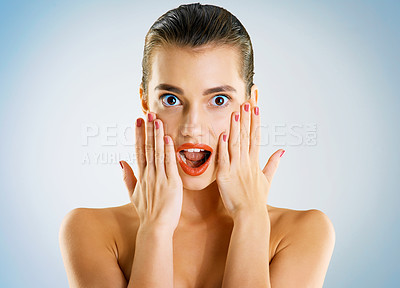 Buy stock photo Studio portrait of a beautiful young woman looking surprised against a blue background