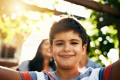 Buy stock photo Portrait of an adorable little boy taking a selfie with his parents in the background