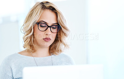 Buy stock photo Shot of an attractive young businesswoman working on a laptop in an office